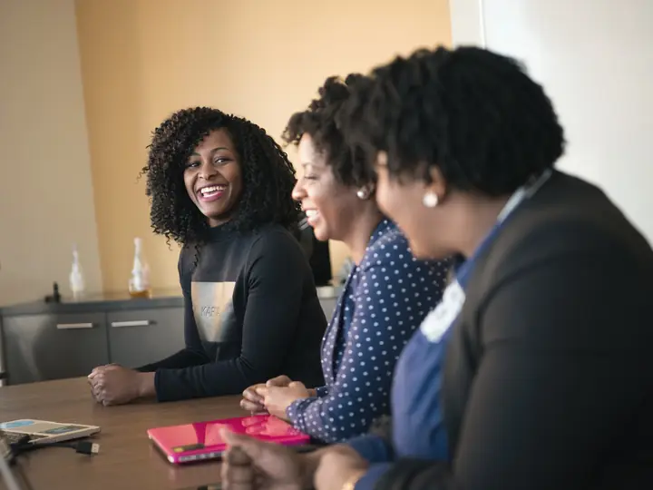 Three colleagues smiling during a meeting at a boardroom table